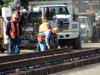 The rail is measured by two workers. They measured the length and spacing, made a few more adjustments with the Cat and then started on the rail with rubber mallats.